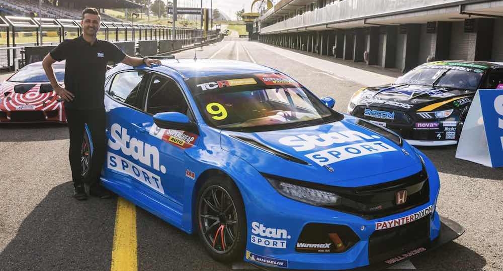 man standing next to a blue race car