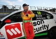 John Bowe leaning against Wilson Security Car with Fastrack V8 Supercar at Sandown Raceway
